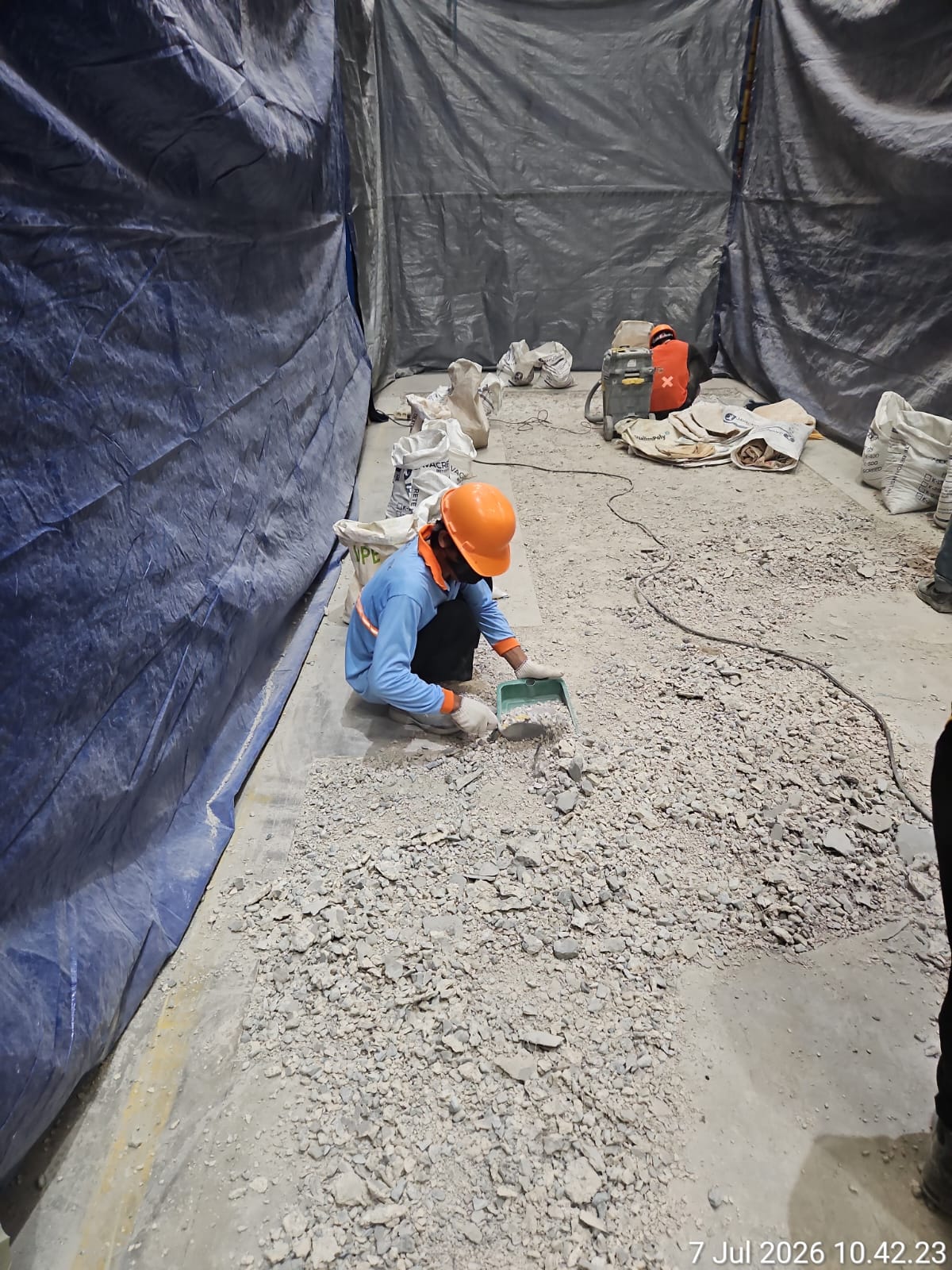 Area kerja perbaikan beton yang terlokalisasi dengan proteksi terpal di fasilitas industri