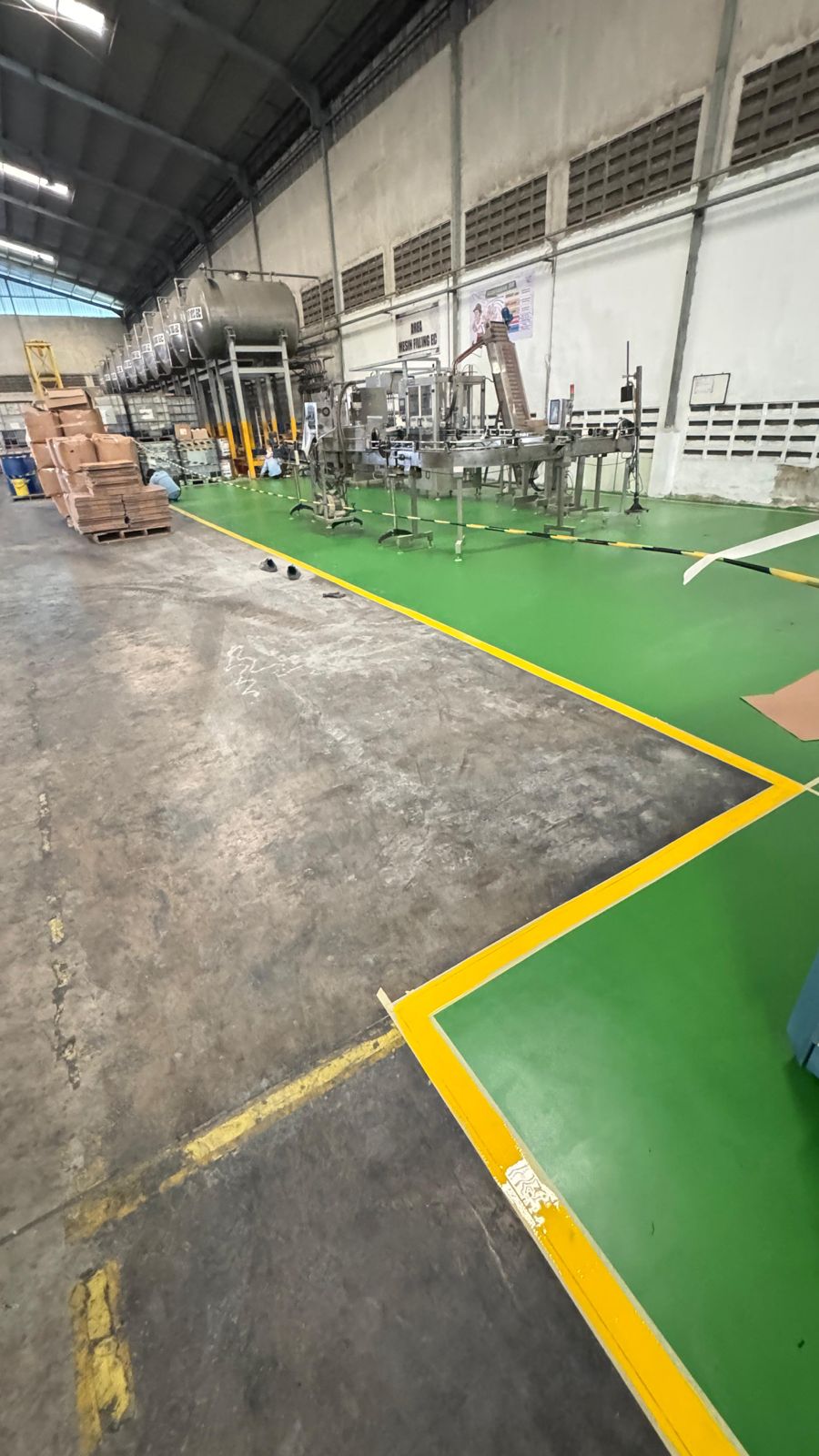 Area mesin filling dengan lantai epoxy hijau dan marking line kuning sebagai pembatas area