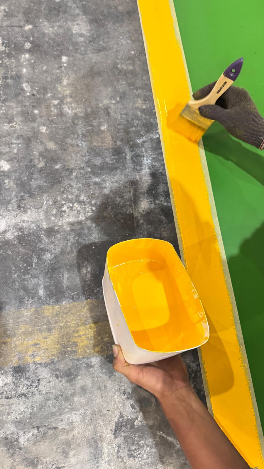 Proses aplikasi marking line kuning di atas lantai epoxy area produksi
