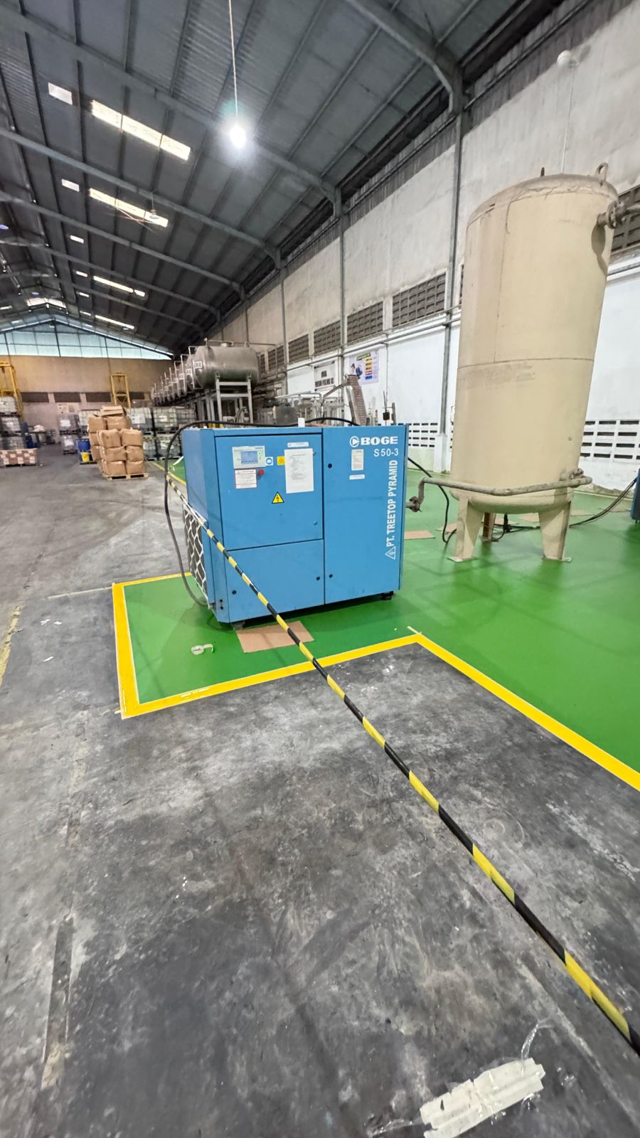 Marking line kuning sebagai batas area mesin kompresor di lantai epoxy pabrik