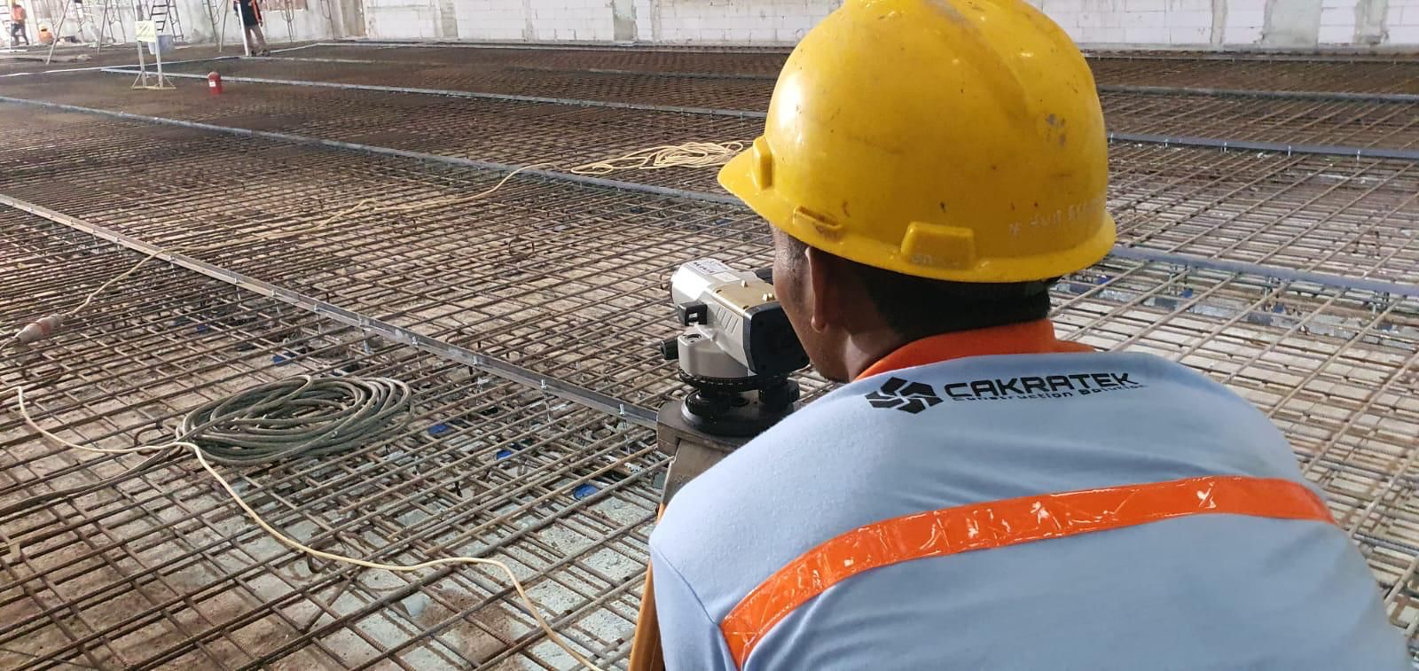 Surveyor Cakratek melakukan pengukuran elevasi lantai beton menggunakan automatic level sebelum pengecoran