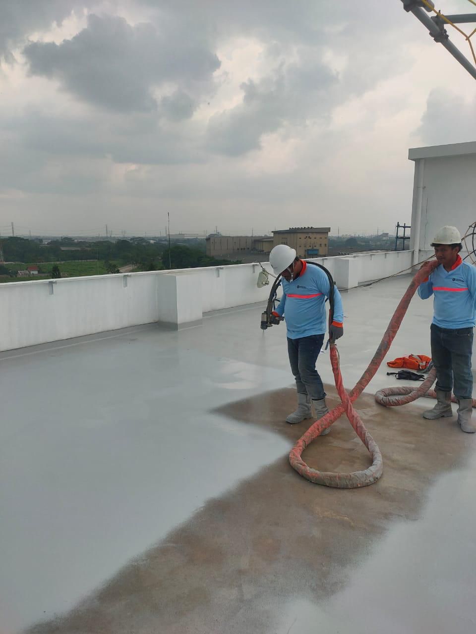 Tim aplikator melakukan spray waterproofing pada rooftop
