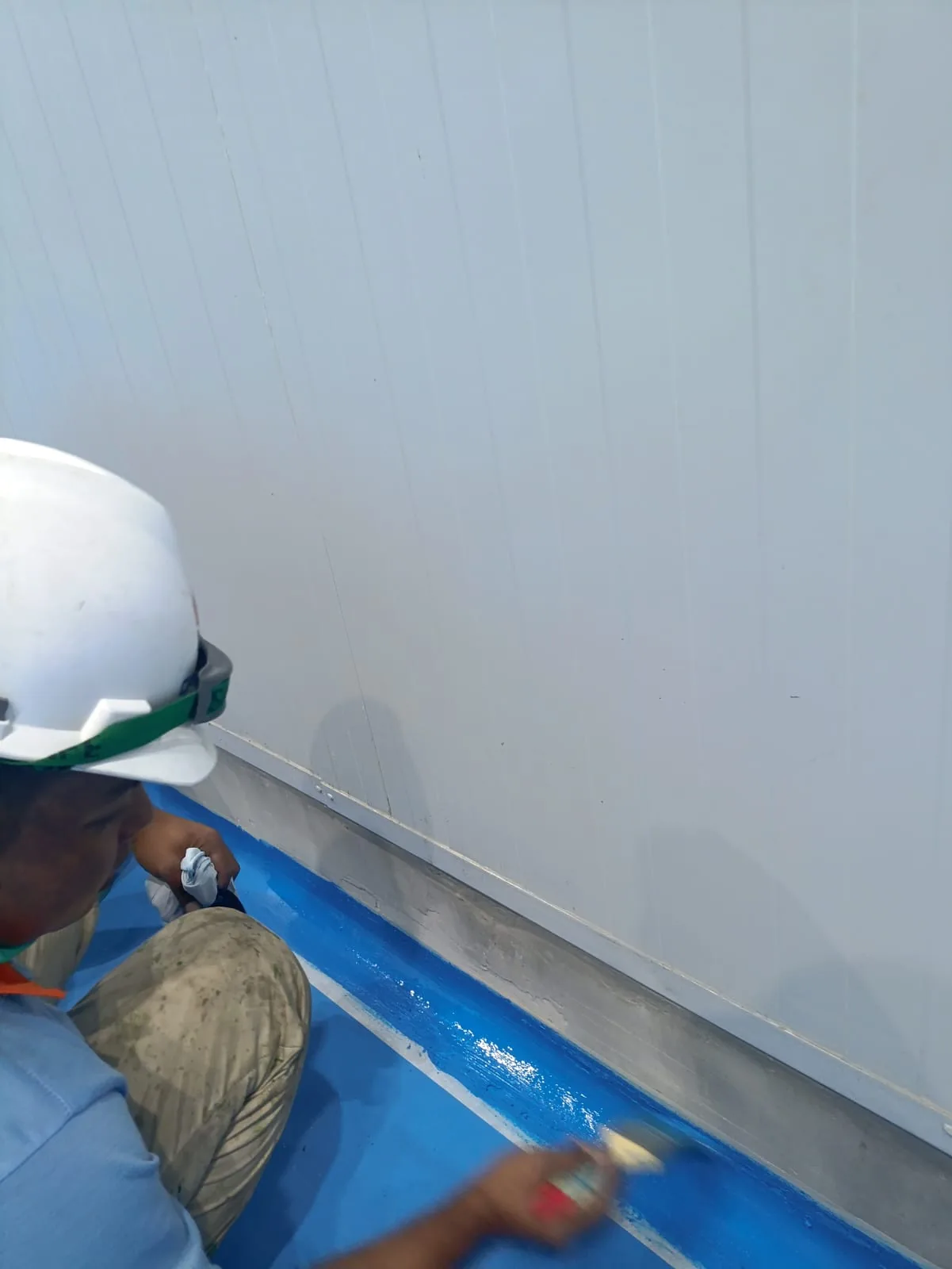 Pekerja meratakan coating biru pada area body curving epoxy