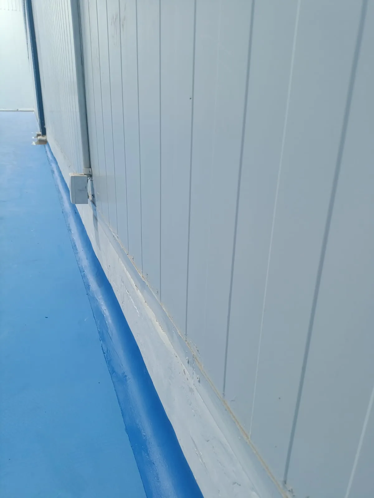 Jasa body curving epoxy untuk pabrik pada tahap finishing lantai biru di tepi dinding