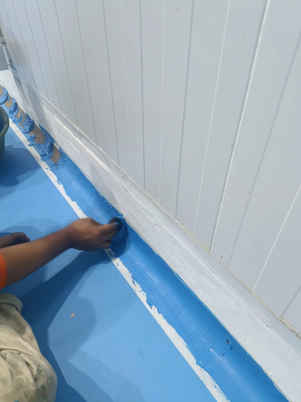 Pekerja melakukan pemerataan material finishing pada body curving lantai industri
