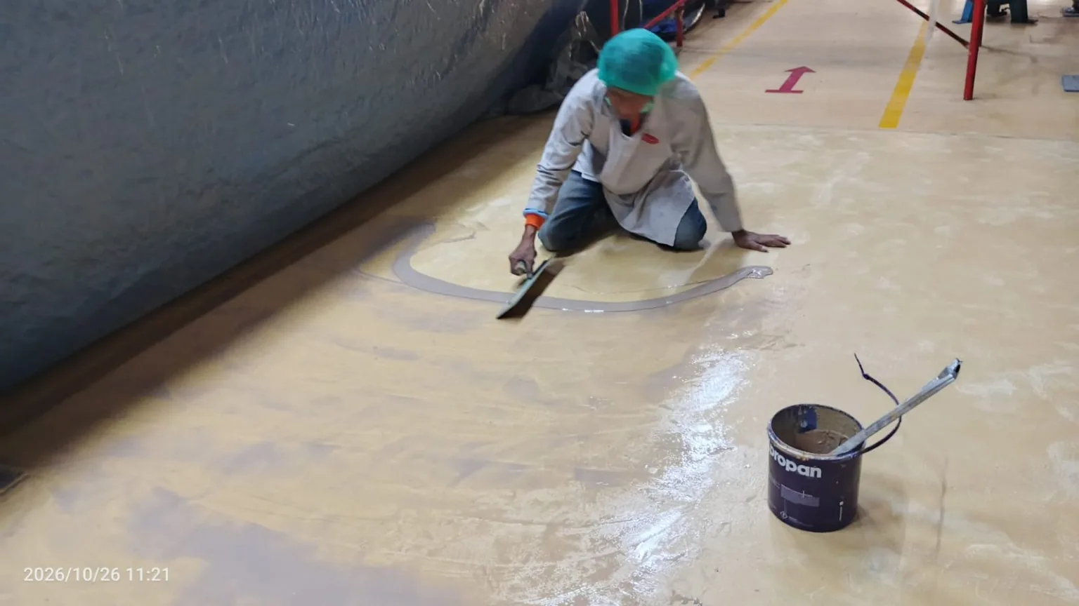 Pekerja meratakan material mortar pada lantai pabrik