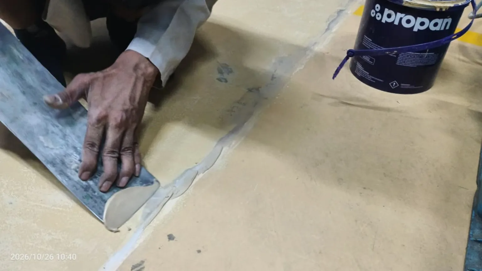Pekerja meratakan mortar pada sambungan lantai pabrik